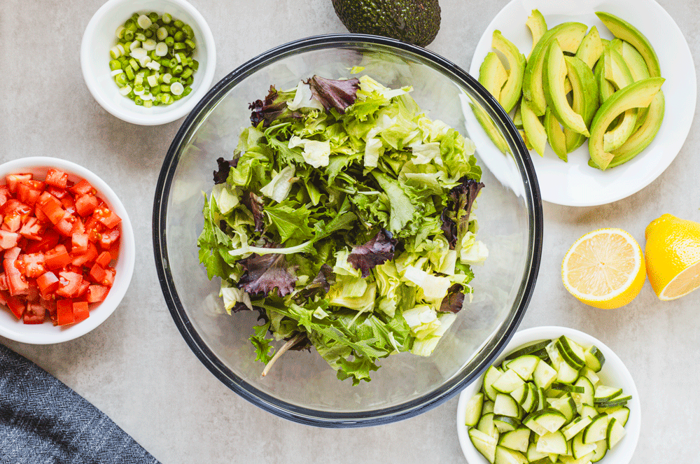 Fresh salad ingredients arranged around mixing bowl.