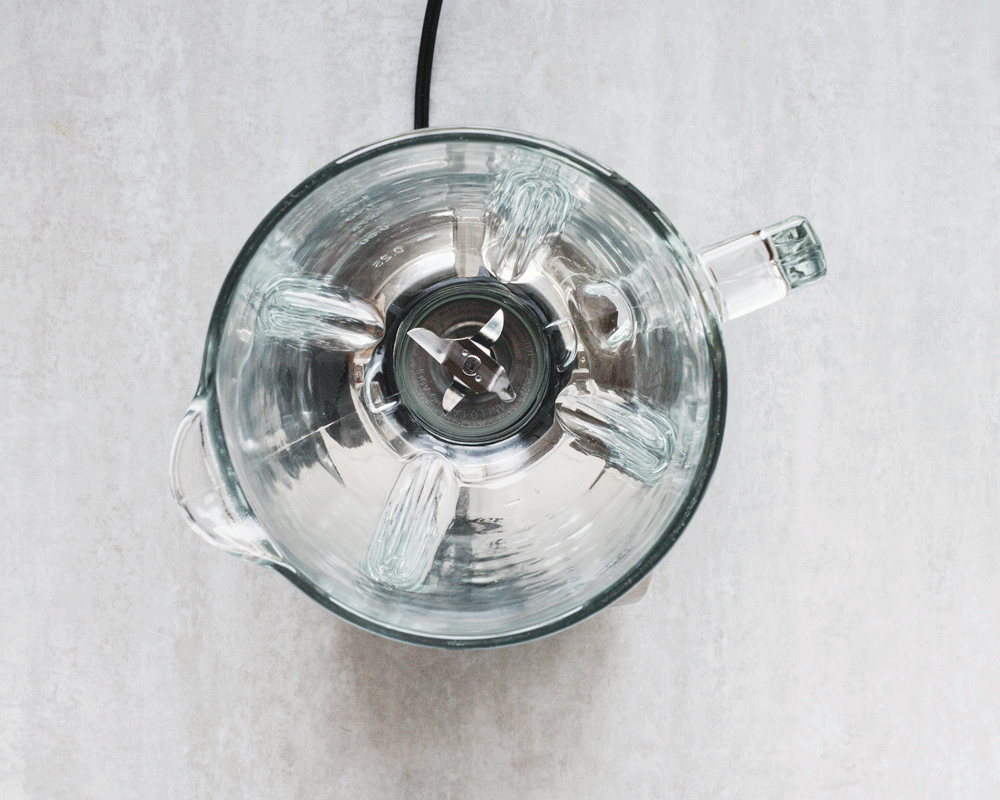 Blender jar rotating with fruit slices inside.