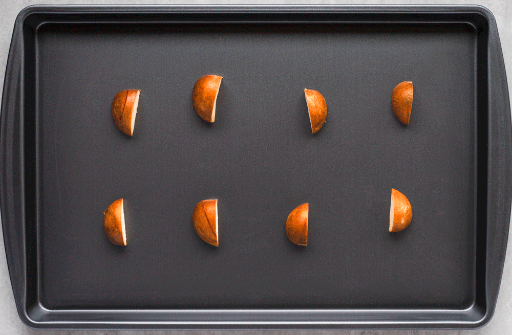 Halved pears arranged on a black baking sheet.