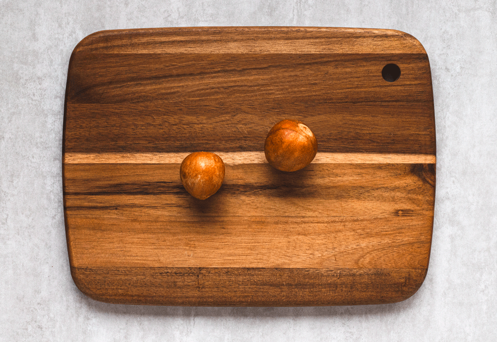 Two mushrooms on wooden cutting board.