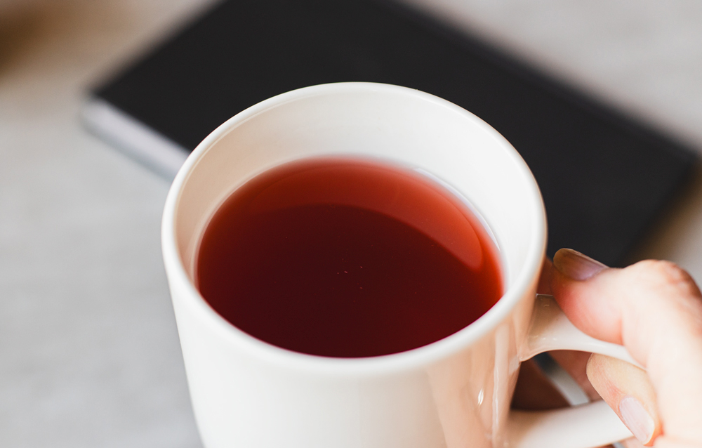 Hand holding a cup of red tea.