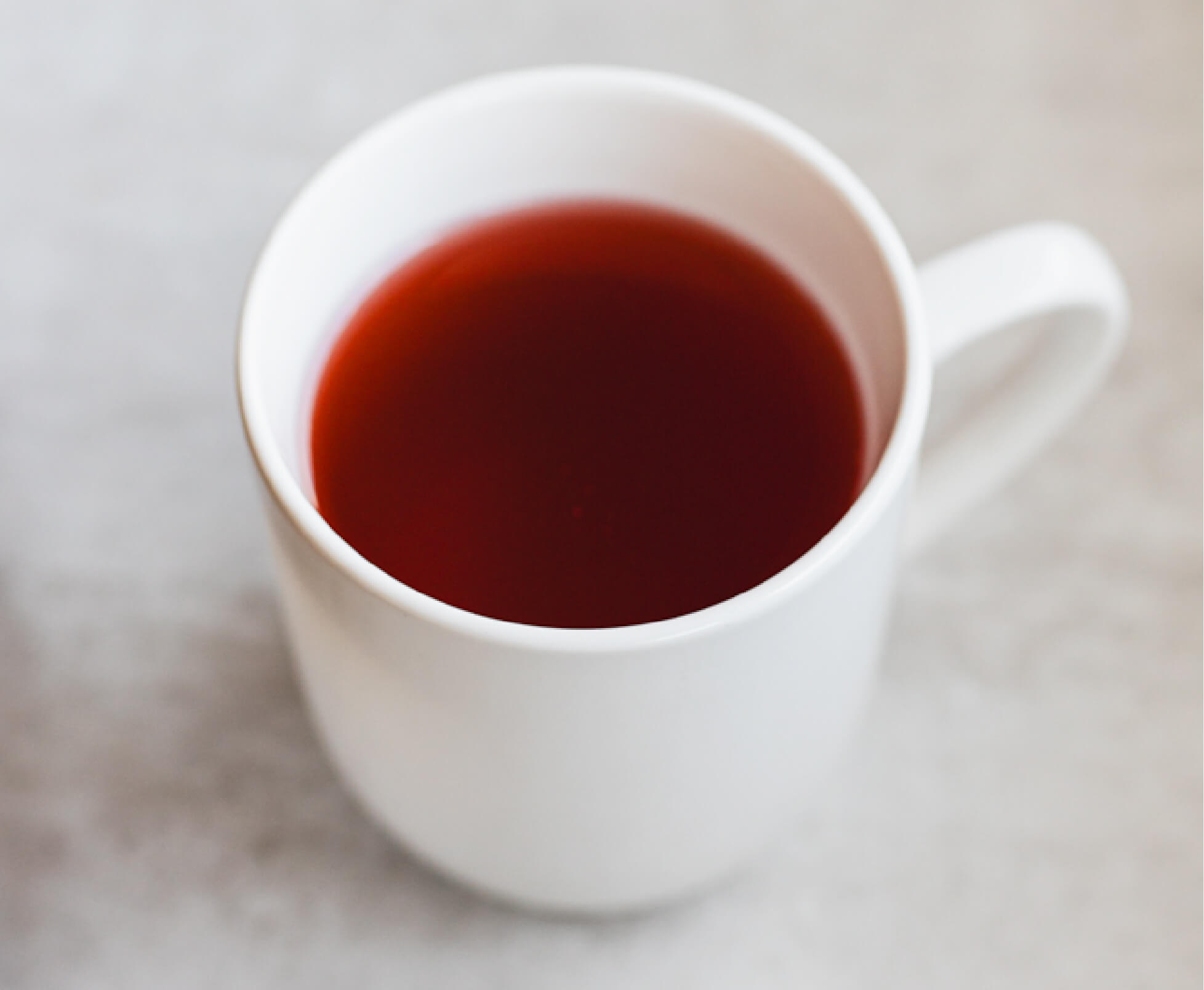 White mug filled with dark red tea.