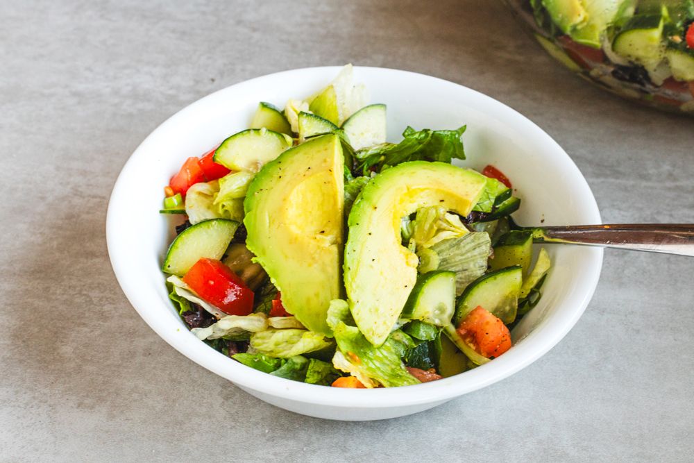 Bowl of fresh salad with sliced avocado and vegetables.