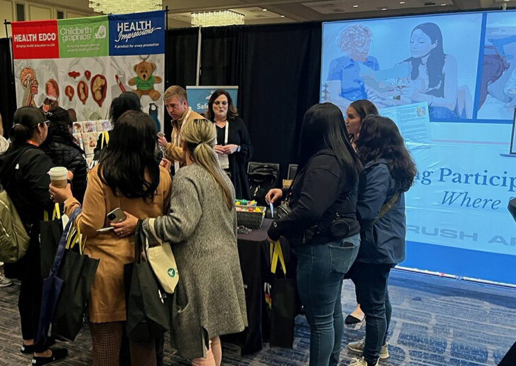 People engaging at health information booth, carrying bags.
