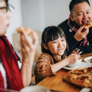 Family enjoying meal with smiles at dining table.