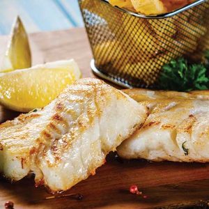 Grilled fish with lemon wedges and herbs.