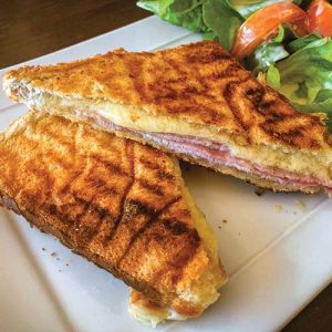 Grilled ham and cheese sandwich with fresh salad.