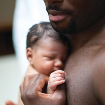 father-baby Father holding sleeping newborn baby warmly.