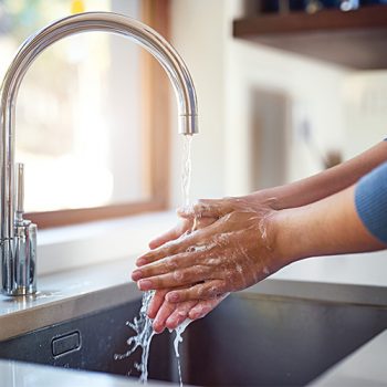handwash Hands washing under running water in kitchen sink.