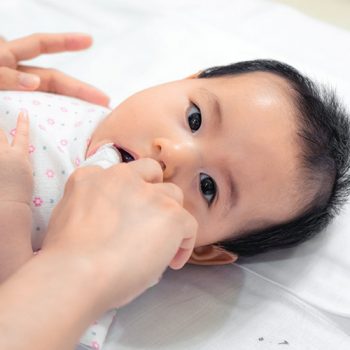 play-babys Baby receiving oral care with adult's gentle hands.