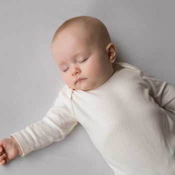 sleep-baby Sleeping baby in white outfit on soft surface.